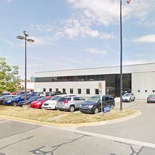 Exterior view of a modern car dealership facility with vehicles parked in the front lot.